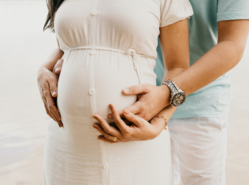 Ein Paar hält liebevoll den Babybauch der Frau in Händen